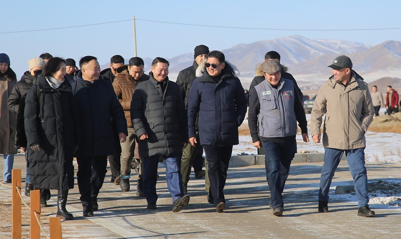 The presidential delegation and farm staff walking through the Nuudelchin Agro Farm site during the December 2024 visit